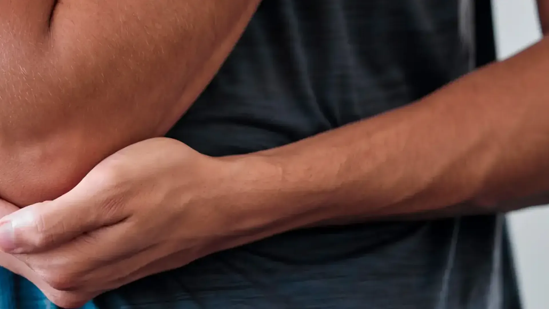 A man holding his forearm just below the elbow, the tendon pain pattern treated at HJ Manhattan Physical Therapy in New York