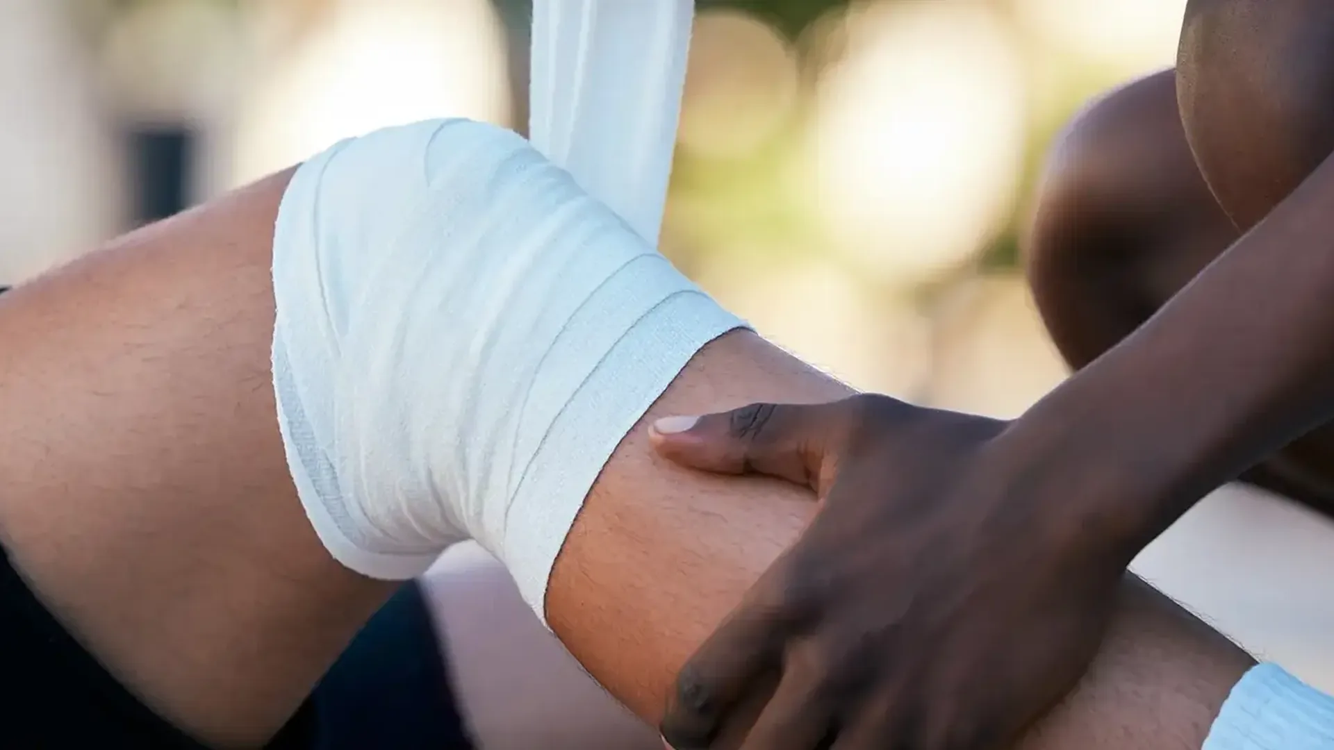 A hand checking the leg beside a bandaged knee, the kind of hip and knee pain treated at HJ Manhattan Physical Therapy in New York