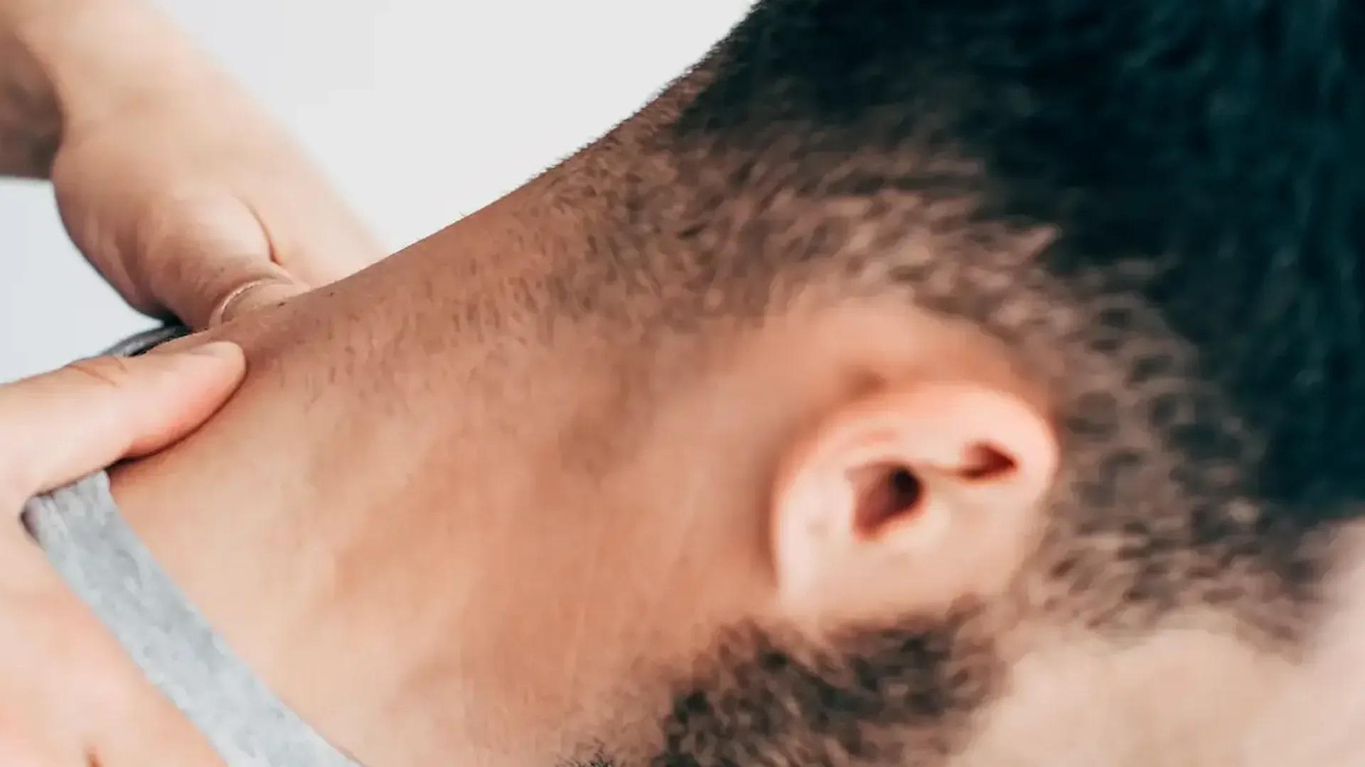 A therapist's fingers resting along the side of a man's neck during a hands-on assessment at HJ Manhattan Physical Therapy in New York