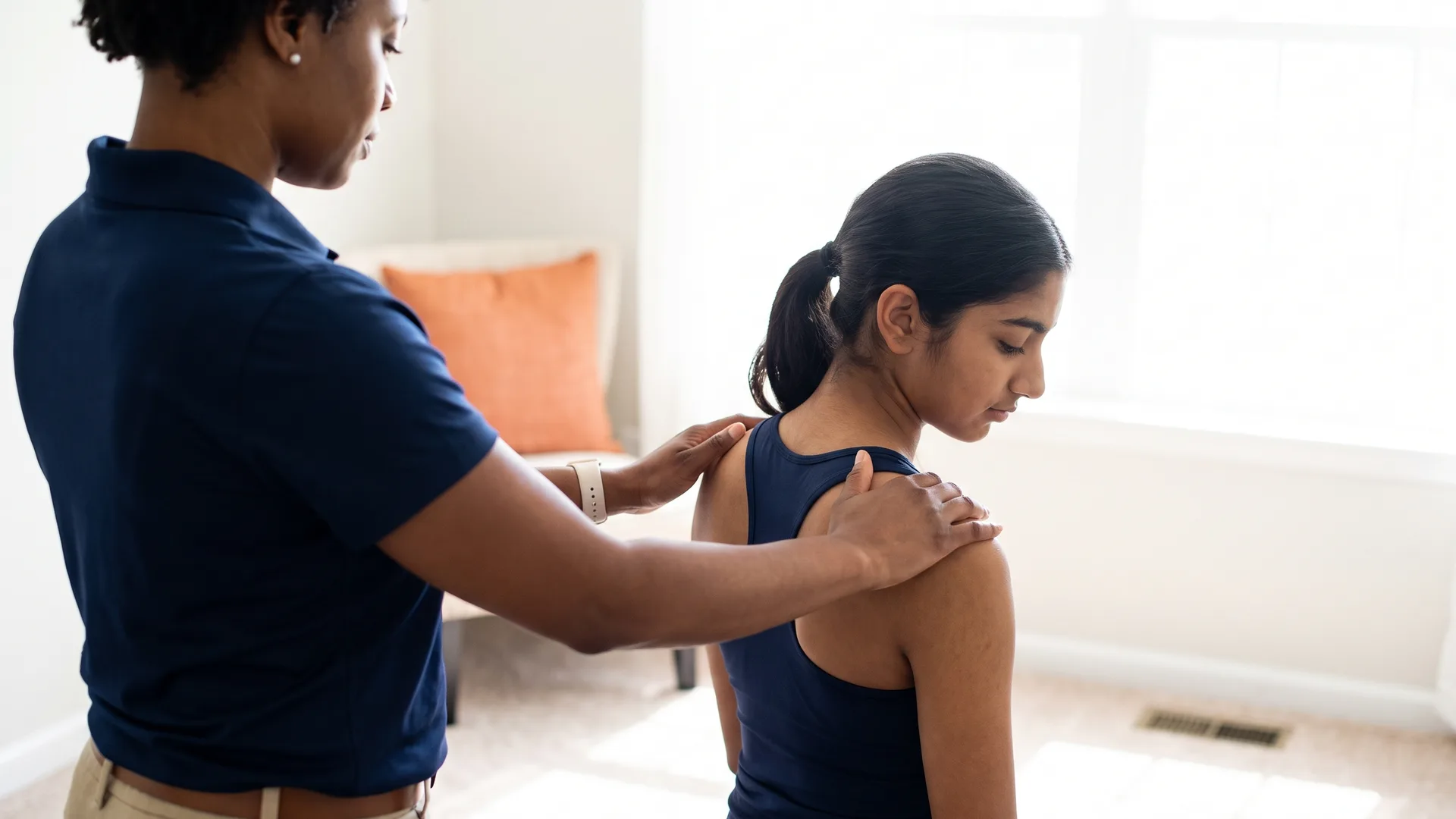 A therapist checking a patient's shoulder and posture alignment from behind